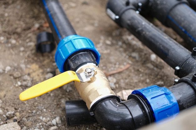 Closeup of elbow fitting of pvc pipes at bend with yellow\
faucet underground irrigation system