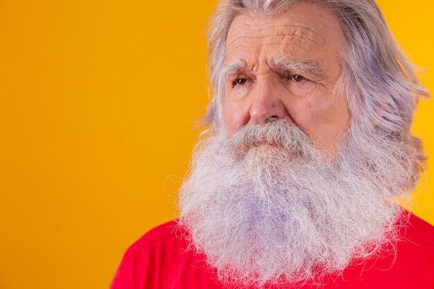 Closeup of an elderly Caucasian bearded man on yellow background.