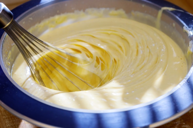 Closeup of electric mixer with whipped smooth dough for cake. 