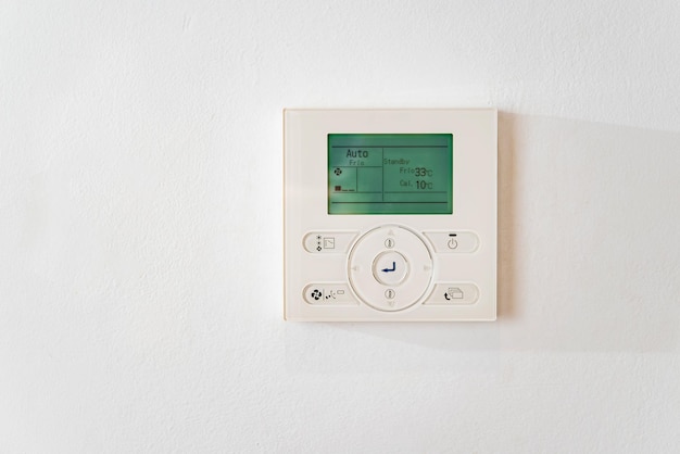 Closeup electronic thermostat on a white wall