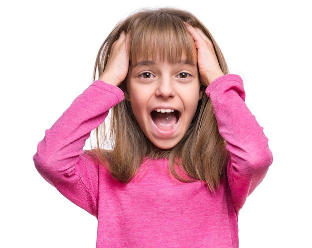 Foto ritratto emotivo in primo piano di una attraente ragazza caucasica con le mani sulla testa sbalordita o sorpresa bella scolaressa che guarda la telecamera divertente carino allegro bambino isolato su sfondo bianco