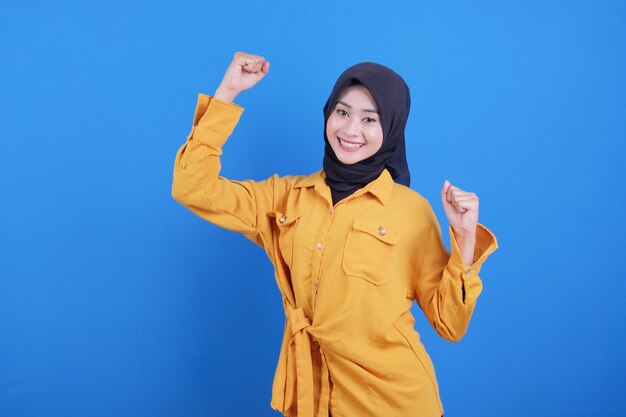 Closeup of emotional young woman isolated on blue wall showing white teeth