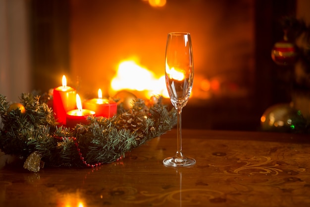 Closeup of empty champagne flute on Christmas dinner table in front of burning fireplace