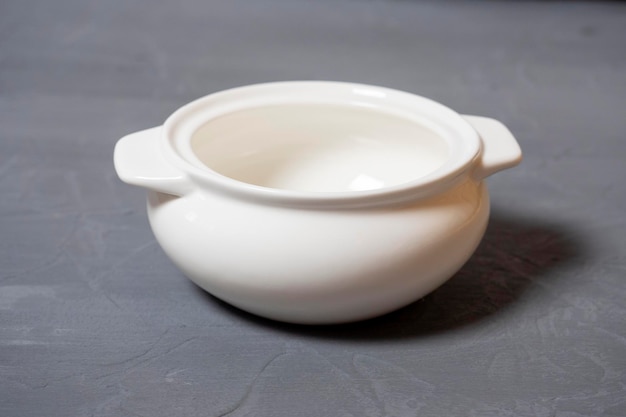 Closeup of an empty tureen made of white porcelain standing on a textured gray background Dishes for food Side view selective focus