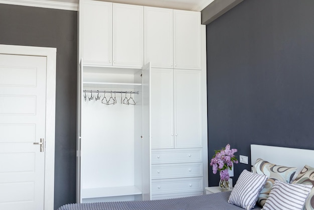 Closeup empty white wardrobe with open doors in a gray room copy paste