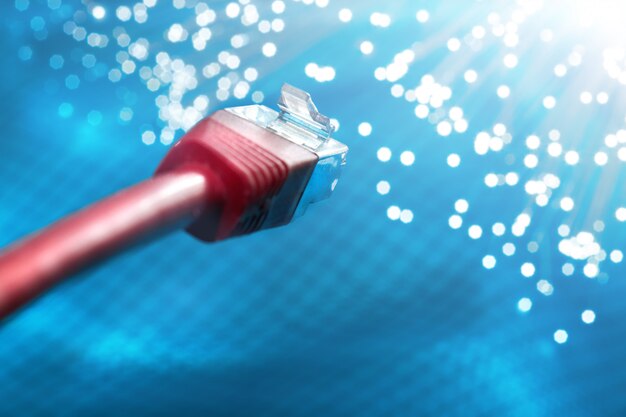 Closeup on the end of red optical fiber network cable on\
blue