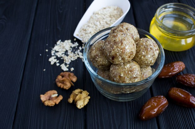 Closeup on energy balls with walnuts, oats cereals, dates and honey in the glass bowl