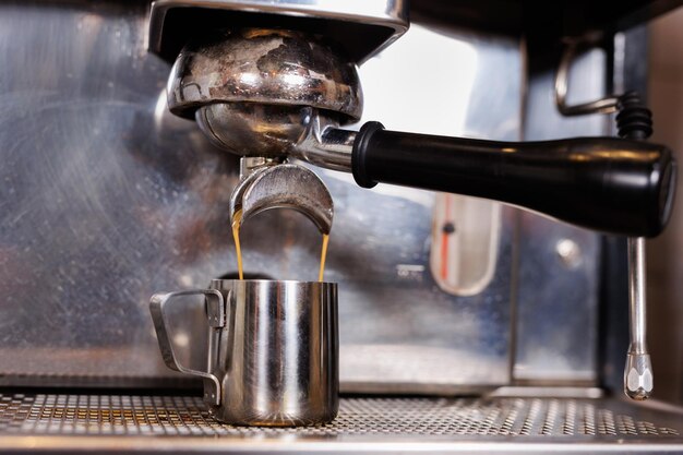 Клоуз-ап эспрессо, наливаемого из кофейной машины Профессиональное заваривание кофе