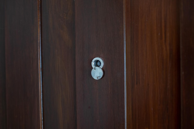 Closeup eye door on wood background peephole