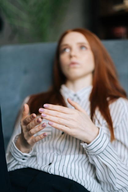 Closeup face of depressed redhaired young woman talking about her problems at psychologist appointment Upset lady patient lying in comfortable armchair during psychotherapy session