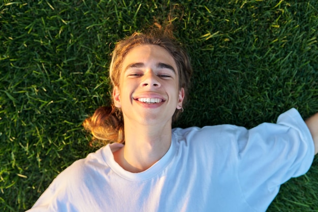 Closeup face of handsome guy 16 17 years old on green grass top view