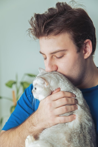 可愛いイギリス猫を抱いている男の顔のクローズアップ