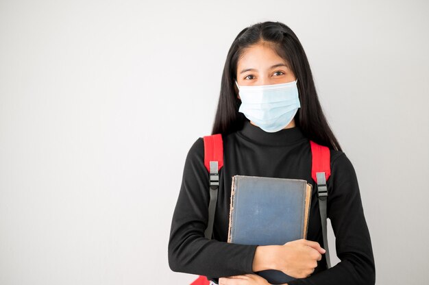 Ritratto del viso del primo piano studenti asiatici universitari femminili indossano una maschera e mantengono le distanze sociali durante l'orario scolastico.