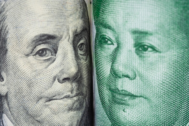 Крупным планом лицом к лицу бенджамина франклина и мао цзэдуна от банкнот доллара сша и китайских юаней.