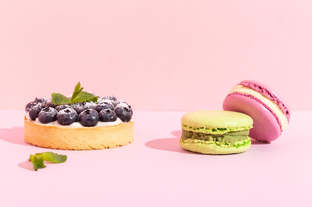 Closeup of fancy gourmet fresh blueberry dessert tarts and French macarons on pink. High quality photo