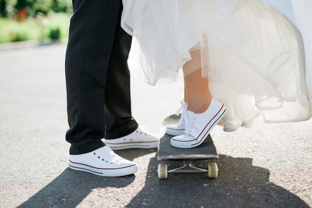 Closeup of feet of bride and groom with skateboard