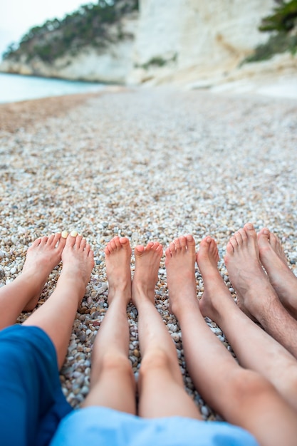 Closeup of the feet of family on the white sandy beach