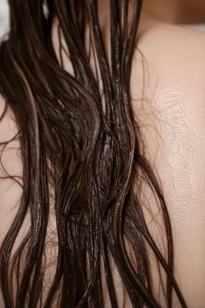 Closeup of female back with wet hair strands covered with conditioner