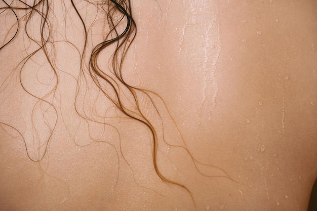 Photo closeup of female back with wet hair strands