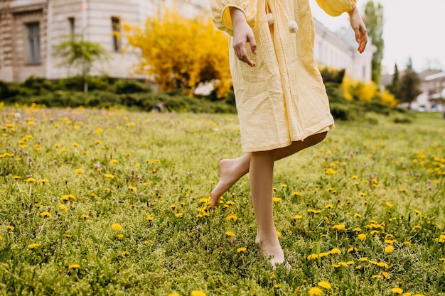 Closeup of female barefoot legs in a field with green grass and flowers