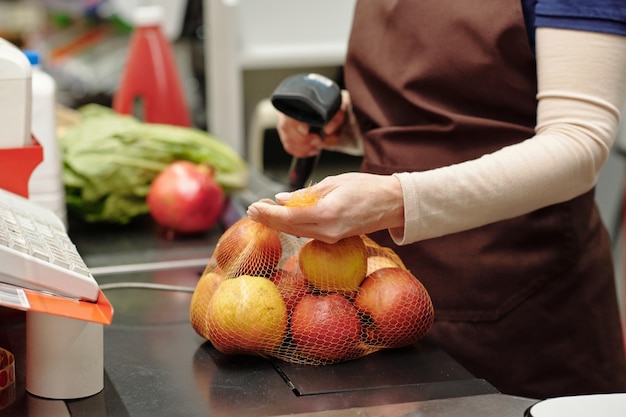 Closeup of female cashier scanning label on pack of apples