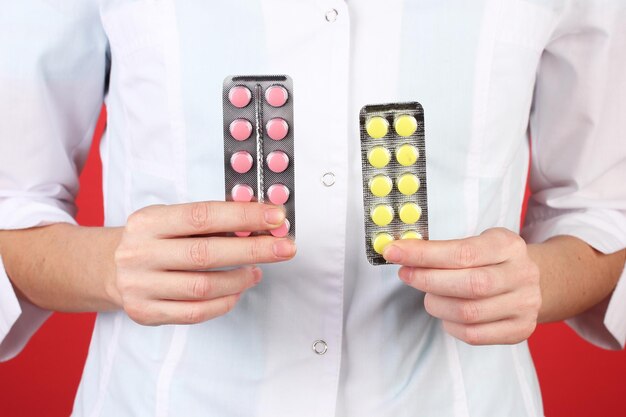 Closeup of female doctor hand holding pills on color background