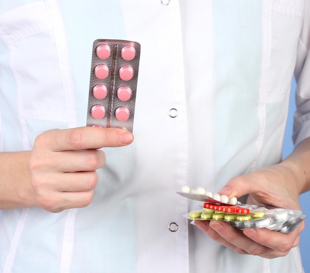 Closeup of female doctor hand holding pills on color background