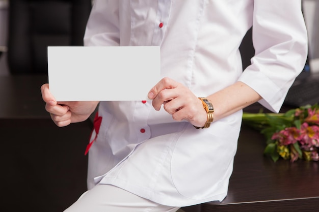 Closeup of female doctor hands holding mockup friendly template of postcard certificate