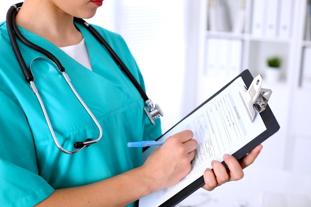 Closeup of a female doctor is filling out application form or medical history