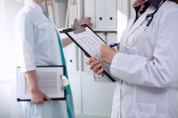 Closeup of a female doctor while filling up medical application form