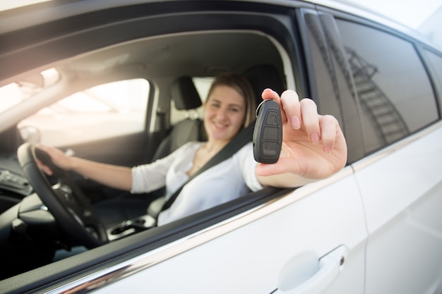 開いているウィンドウから車のキーを示す女性ドライバーのクローズアップ