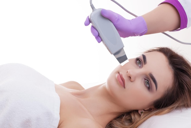 Closeup female face with closed eyes getting ultrasonic peeling in a beauty parlour