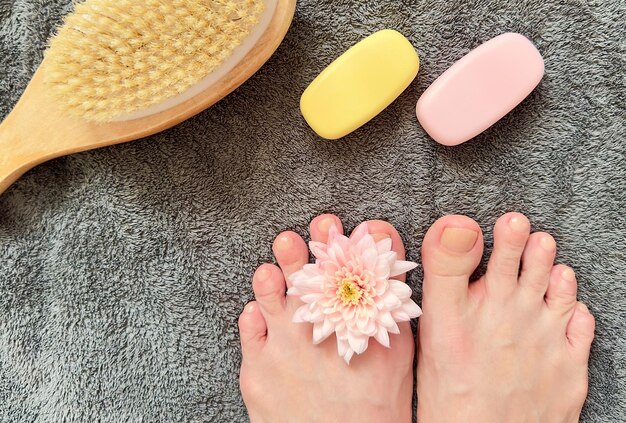 closeup of female feet with rose flower on towel background