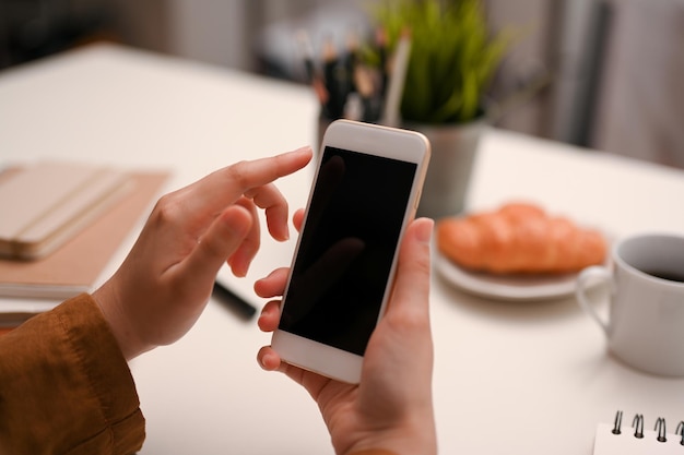 Крупный план Женский палец, печатающий на экране смартфона, макет черного экрана смартфона, обрезанное изображение