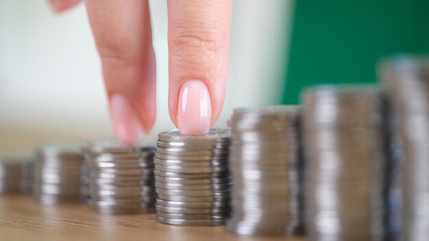 Closeup of female fingers going up on bar chart made of coins\
business growth increase income