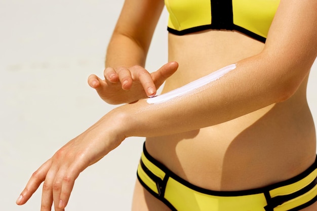 Closeup on female hand applying sun block creme on hand at the beachSkin Care Protection sun cream