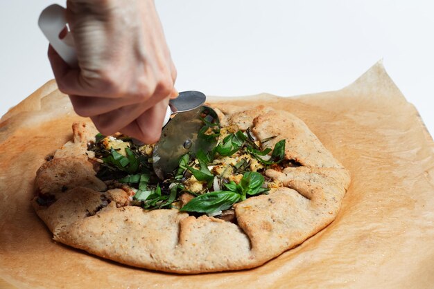 Closeup of female hand cutting galette with pizza knife Homemade vegan food