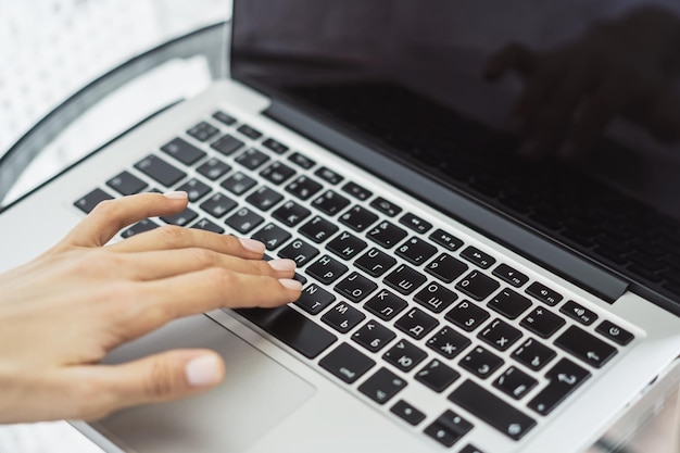 Closeup of female hand presses a button on laptop keyboard top view