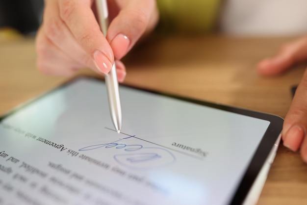 Photo closeup of female hand signing edocument on tablet with stylus electronic signature and modern