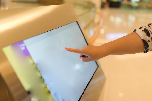 Крупный план женской руки на информационной стойке с сенсорным экраном в торговом центре