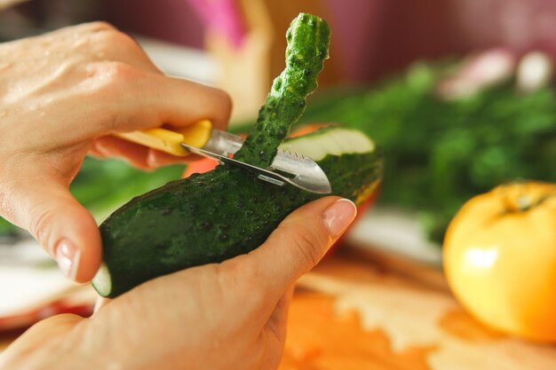 Closeup of female hand with peeler and cucumber