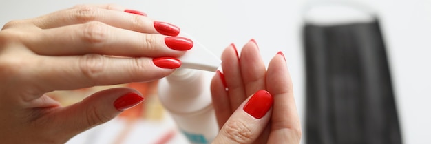 Closeup of female hands applying antiseptic bottle with disinfectant and protective face mask