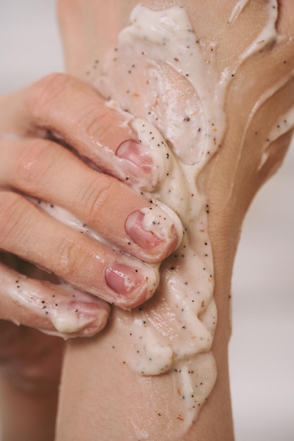 Foto primo piano delle mani femminili coperte di scrub naturale per la cura del corpo