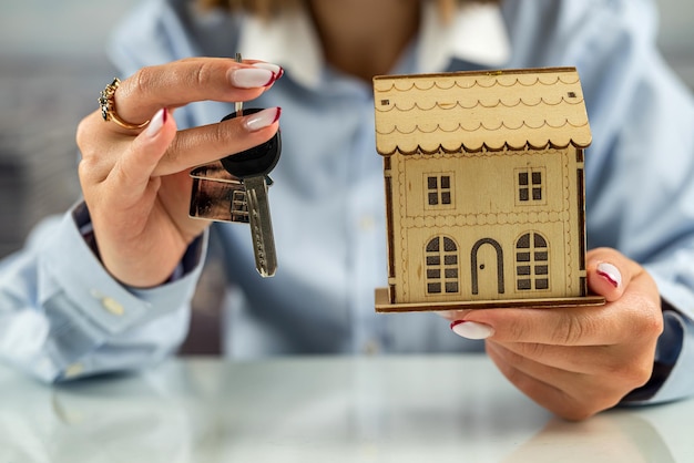 Closeup of female hands covering a modern house Home protection concept Housing insurance