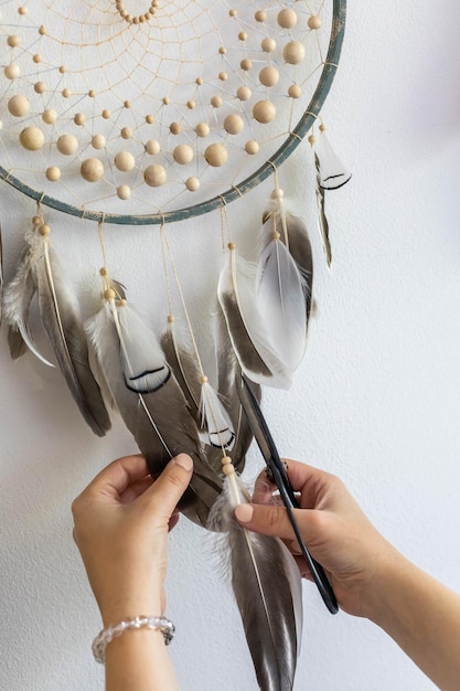 Closeup female hands creating traditional tribal culture amulet dreamcatcher with feathers isolated