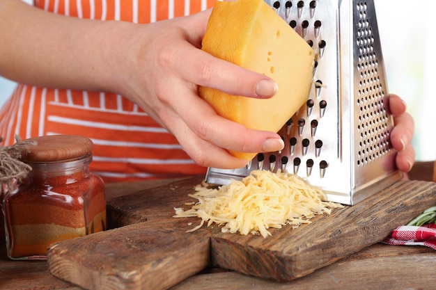 Photo closeup of female hands grating cheese