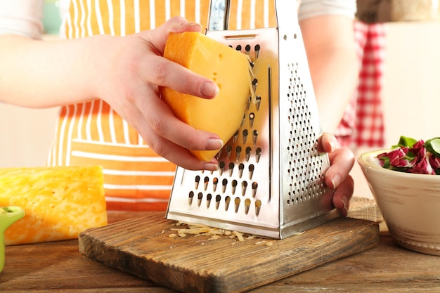 Photo closeup of female hands grating cheese