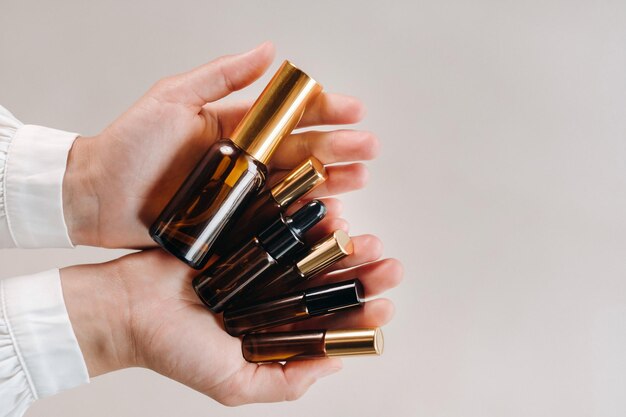 Photo closeup of female hands holding many bottles of essential oil aromatherapy