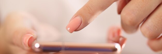 Photo closeup of female hands holding modern smartphone in hands and pointing on screen with finger