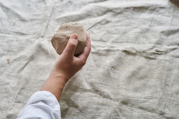 Closeup female hands kneading a piece of clay on the table